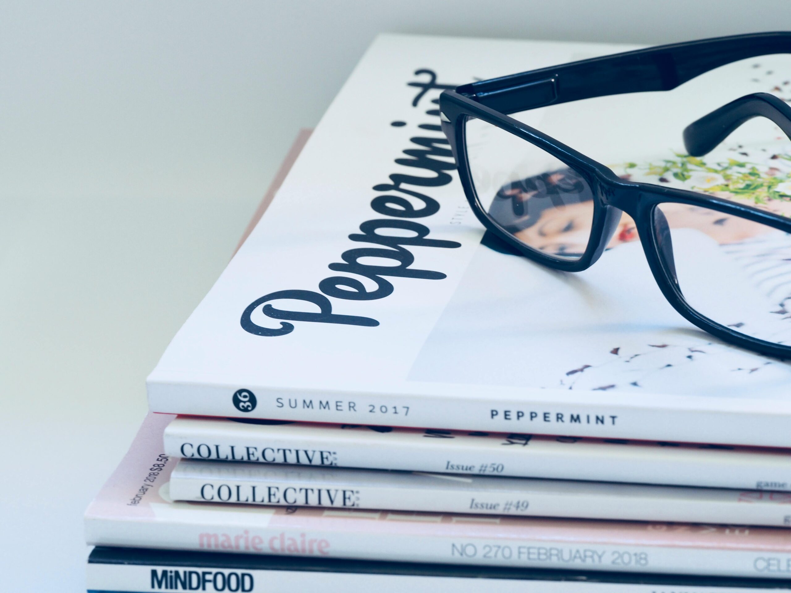 Eyeglasses on a stack of fashion and lifestyle magazines including Peppermint and Collective.